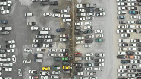 aerial look straight down view over outdoor parking lots with many random type and colour vehicle.