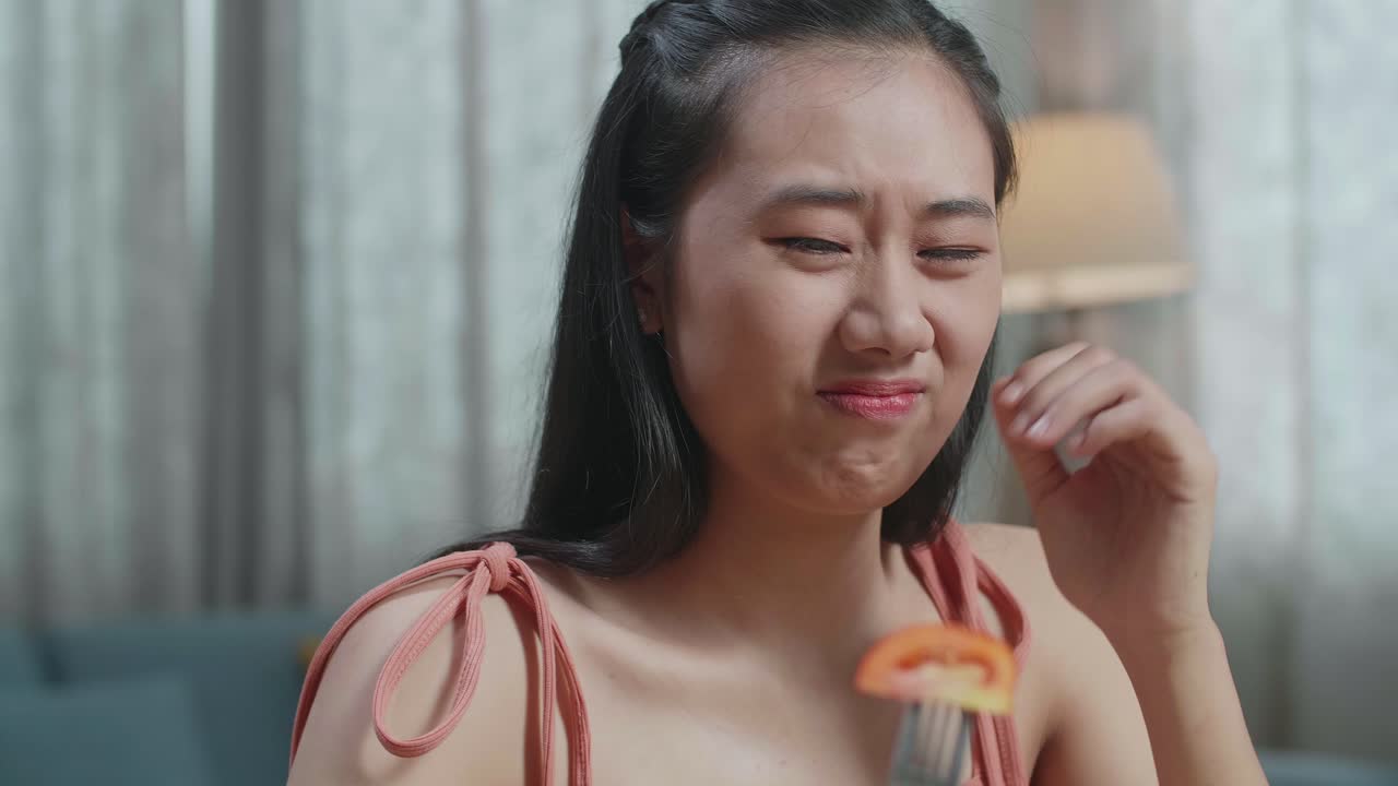 집에서 식사를 하는 동안 건강한 음식을 먹는 것을 싫어하기 때문에 을 잡고 머리를 흔들고 있는 아시아 여성의 근접 사진