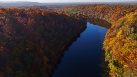 Una-Vista-Aérea-Sobre-Un-Lago-En-Un-Día-Soleado-Con-Coloridos-árboles-Otoñales