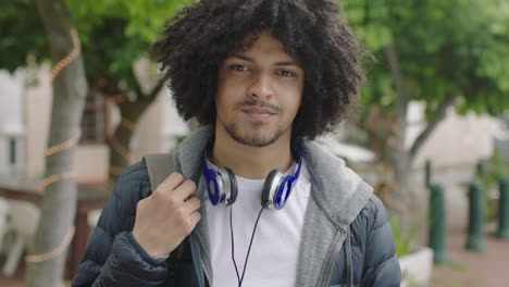 portrait of young male mixed race student smiling happy looking at camera commuting in city enjoying urban lifestyle cool afro hairstyle