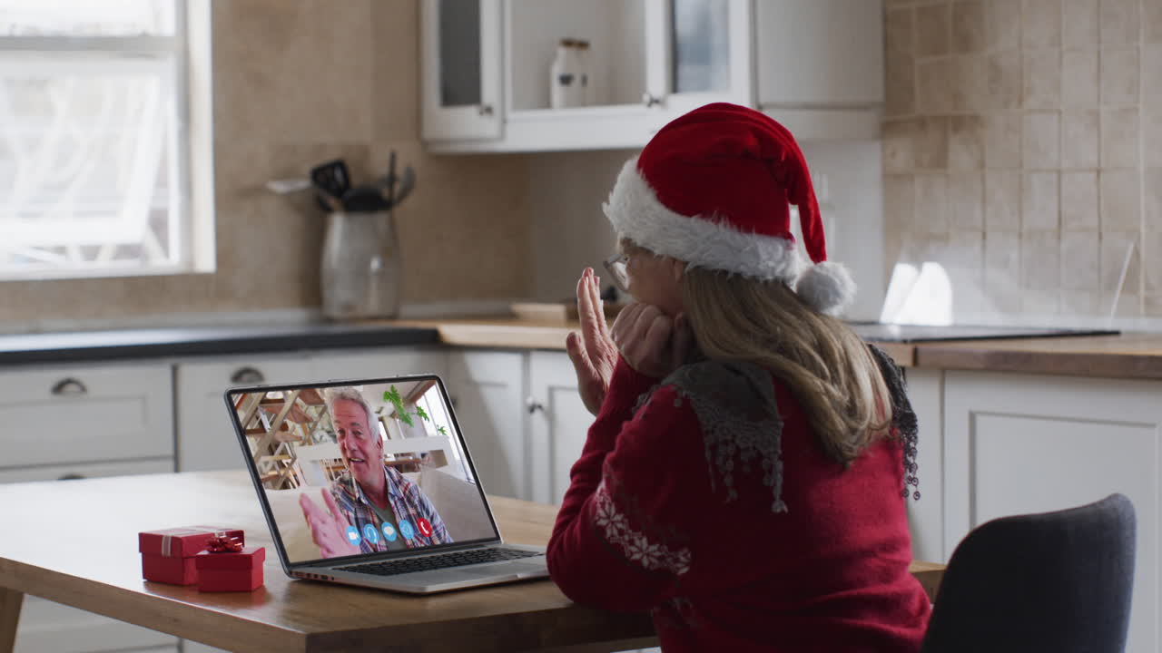 mujer caucásica con sombrero de santa en una llamada de video portátil durante la navidad en casa