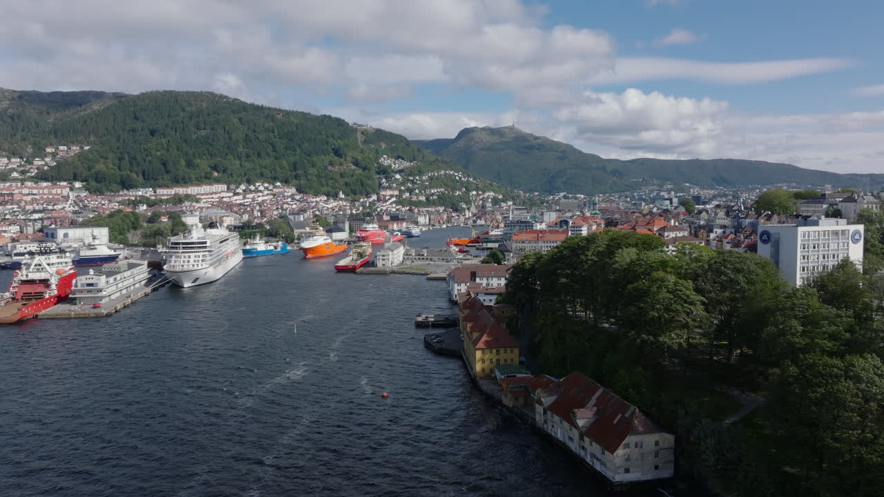 Wide establishing shot of Bergen’s coastline, harbor, and mountain setting in summer