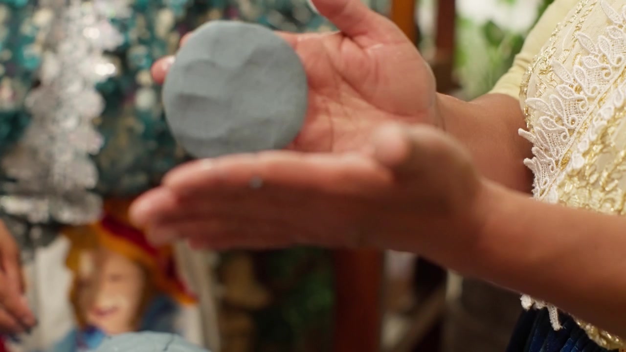 Hands shaping round green tortilla into smooth disc, passing between hands back and forth, gentle finger imprints on nopal tortilla