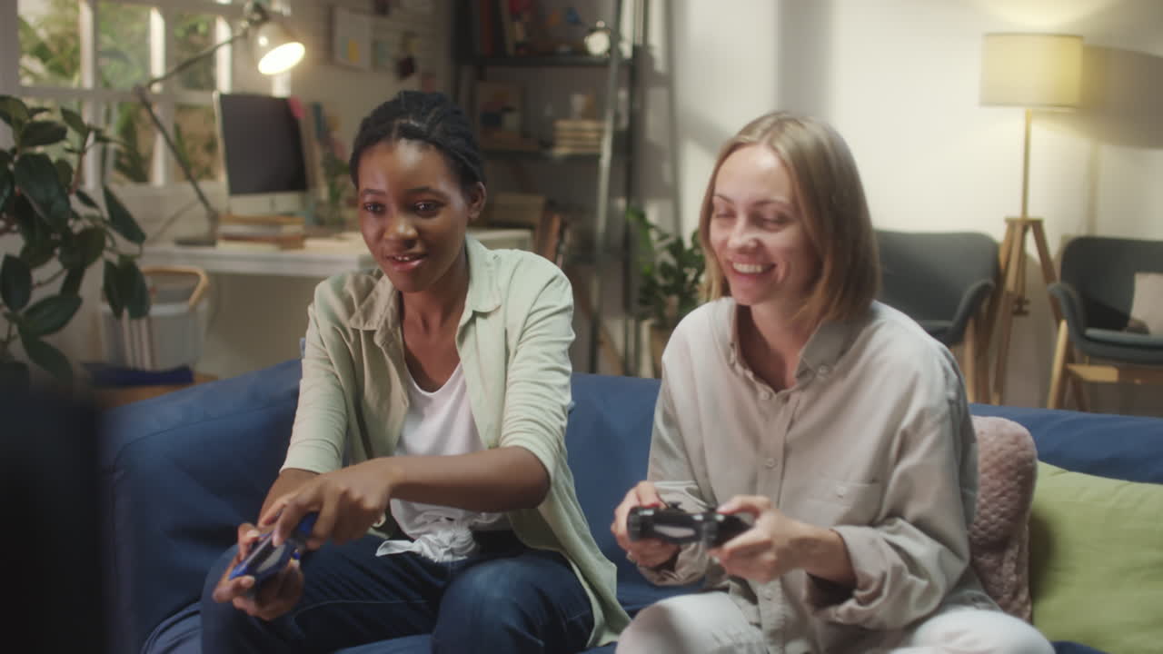 Two Women Friends Enjoying a Video Game Session on the Couch