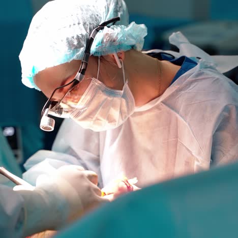 female surgeon doing plastic surgery. professional doctor in medical uniform with special magnifying glasses uses medical instruments in the modern hospital.