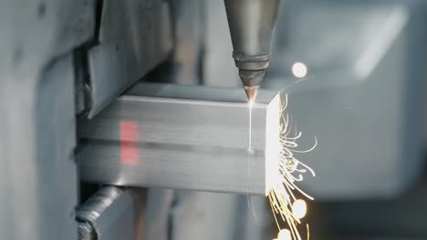 tube laser cutter is cutting through a stainless steel tube with flying sparks