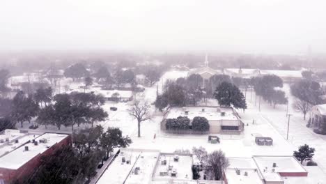 Toma-De-Establecimiento-Descendente-De-Una-Pequeña-Ciudad-En-Invierno-Con-Ráfagas-De-Copos-De-Nieve