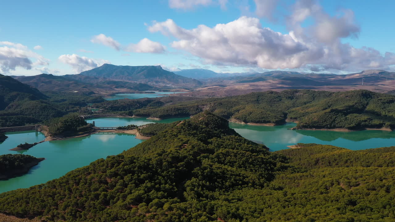 toma aérea de un lago de color cian rodeado de bosques y montañas