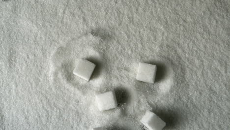 many sugar cubes falling into pile of sugar