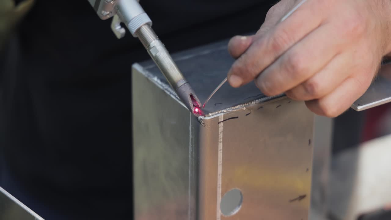 máquina de soldadura láser con pistola de mano. la soldadura láser se muestra en primer plano.