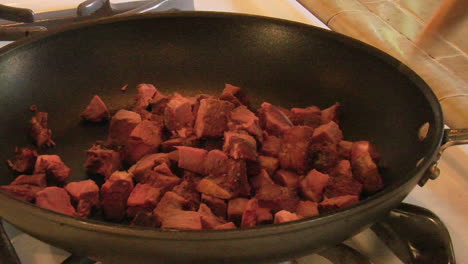 chunks of beef are dropped into a frying pan