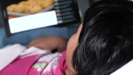 child watching tablet in bed