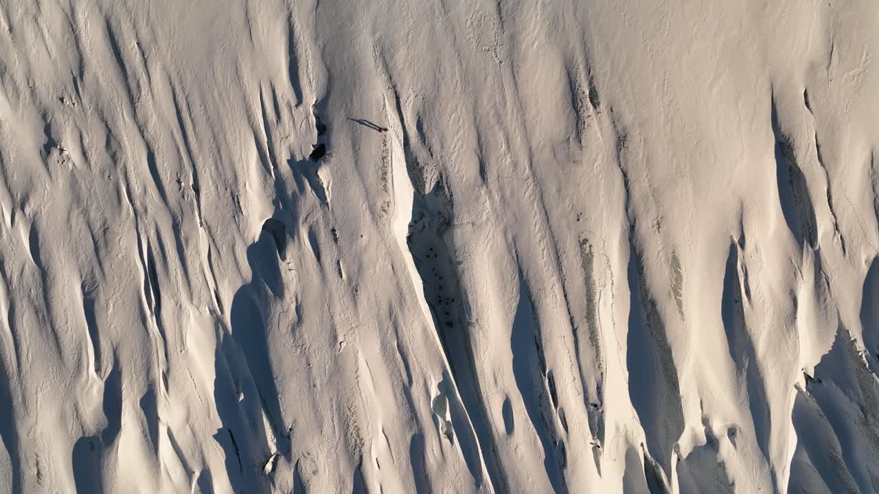Aerial top view over a person standing on Sólheimajökull glacier textured ice, in Iceland