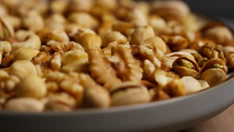 fotografía de cerca de un cuenco giratorio que contiene caju, cacahuetes tostados secos, pistachos, nueces y avellanas 2
