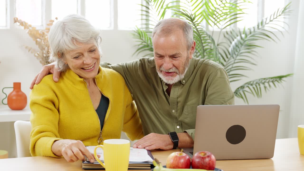 Happy elderly couple using laptop at home