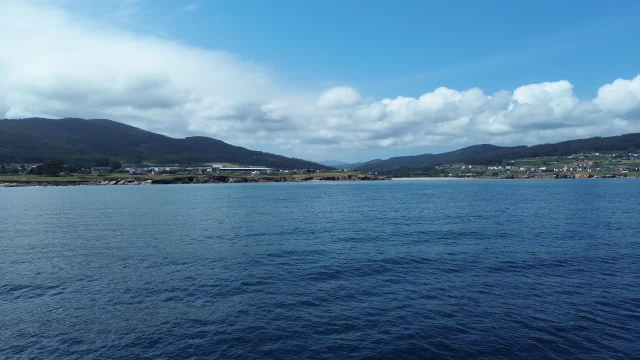 Calm sea and hills under blue sky at Lugo beach, evokes tranquility
