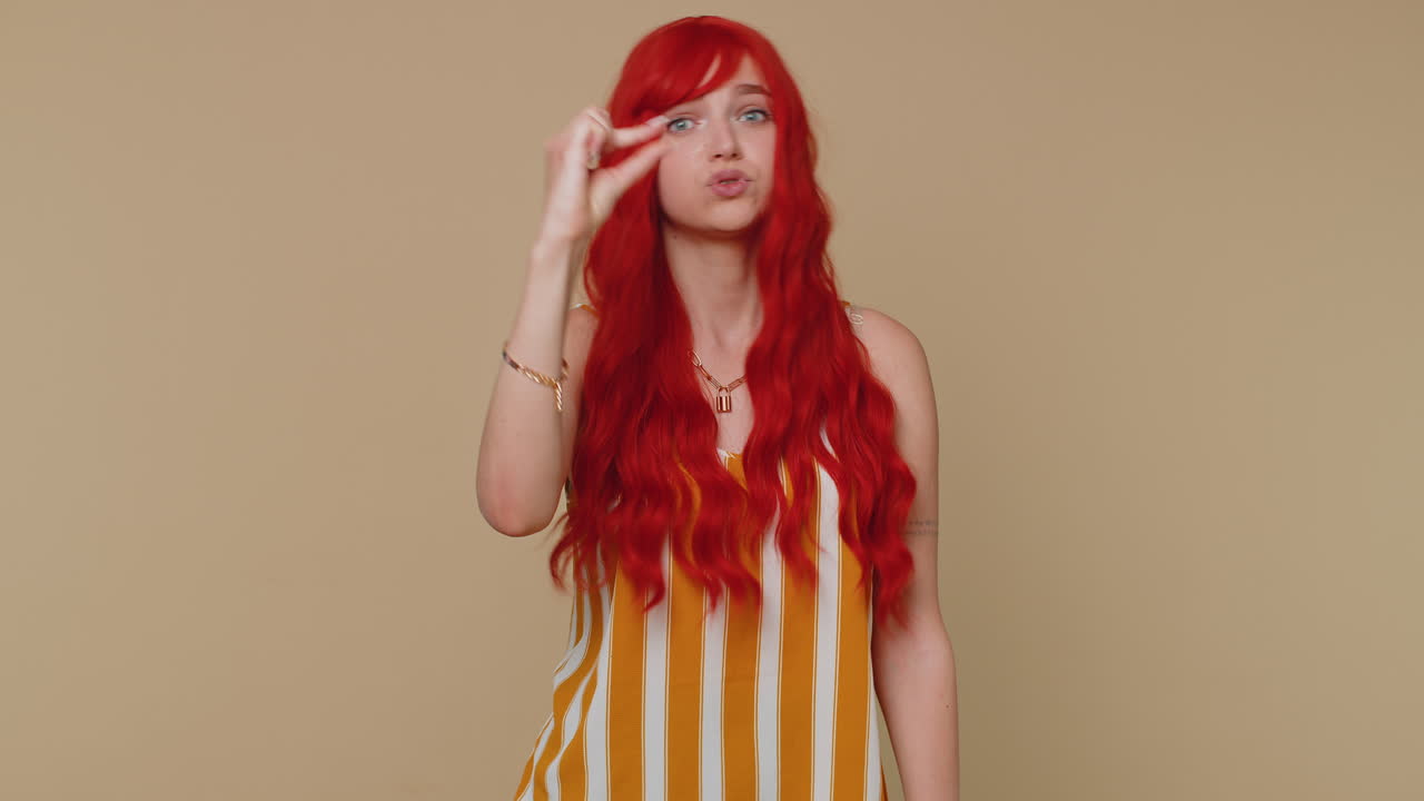 소녀는 회의적인 미소와 함께 약간의 몸짓을 보여주고, 최소한의 기호를 보여주고, 작은 크기를 측정합니다.