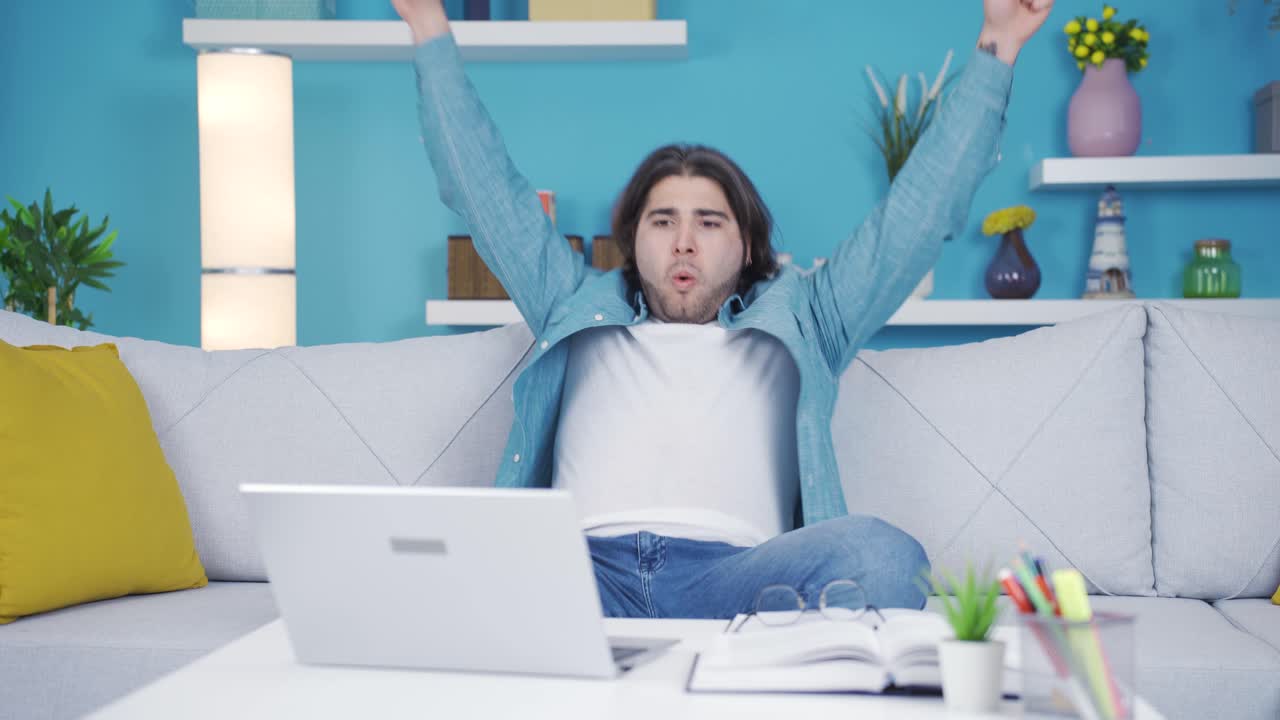 행복한 젊은이가 노트북에서 성공을 거두고 있습니다.