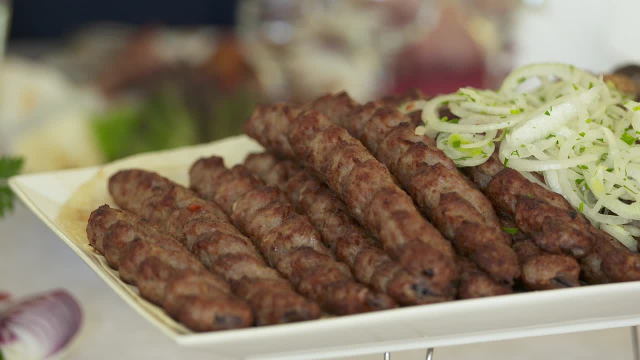 Doğranmış soğanla dekoratif bir tabakta servis edilen Ermeni lüle kebabı.