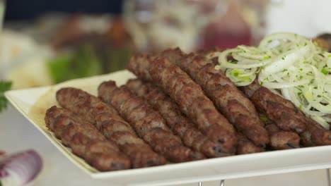 lula kebab armenio servido en una bandeja decorativa con cebolla picada