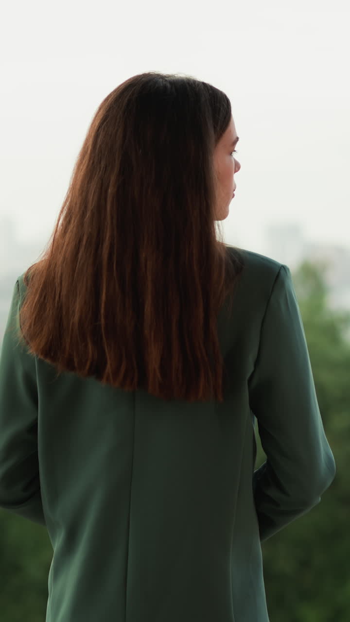 생각 많은 여자가 비가 내리면 건물 지붕 위에 서 있습니다. 사업가는 사무실 테라스에서 진정하려고 노력하는 힘든 소진을 표현합니다. 과도한 작업으로 인한 우울증.