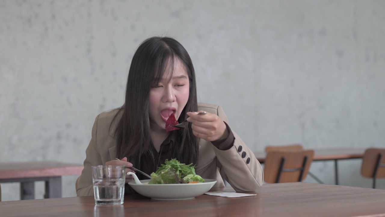 Wanita menuangkan saus salad di atas salad hijau sehat