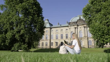 Woman using laptop in park near building