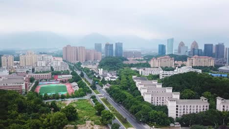 tonglu city, urban scenery, athletic sport field, establishment drone shot, aerial shot, neighbourhood apartments, hazy morning, trees in chinese city, overview in hangzhou, zhejiang province, china