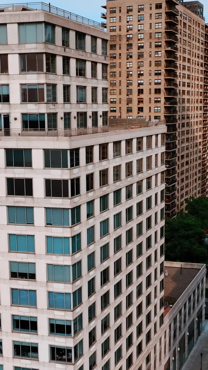 Flight among the top floors of the multistoried buildings. Multiple windows of New York architecture. Vertical video