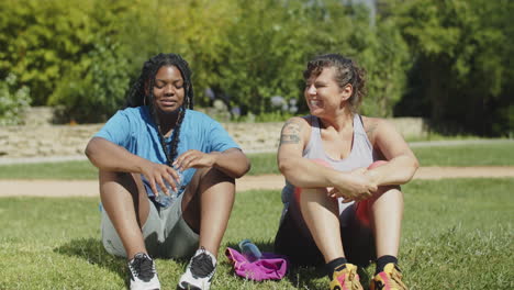 long shot of happy fat women sitting on lawn after training