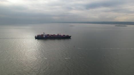vuelo aéreo hacia un barco de contenedores de carga que viaja a través de las aguas del puerto de nueva york