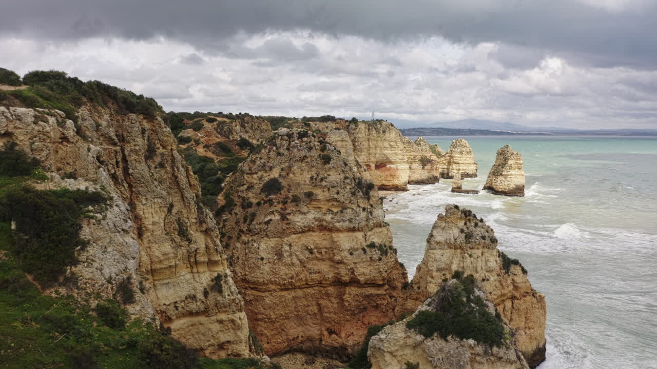 Aerial of Sandstone cliffs along Algarve Coastline with waves crashing through the rocks (Ponta da Piedade)