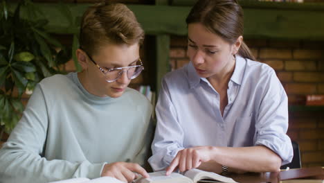 Student-reading-the-holy-Bible-while-her-teacher-is-looking-at-him