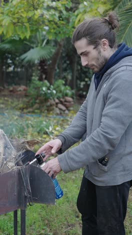 man using a gas torch to light a fire in a backyard