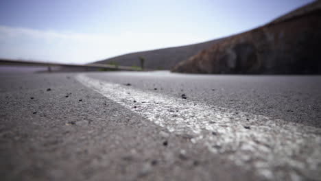 Asphalt-road-white-line-in-mountains-route-with-curves-and-hairpin-bends-with-rock-cliff-and-guard-rail,-extreme-close-up