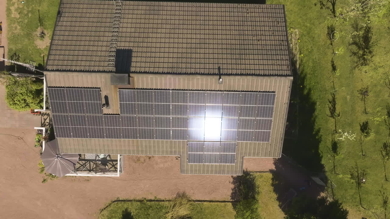 Cenital aerial above a the sun reflecting from Photovoltaic cells on a house roof