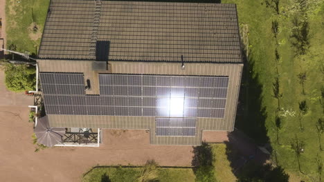 cenital aerial above a the sun reflecting from photovoltaic cells on a house roof