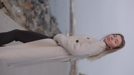 woman in beige coat by the sea