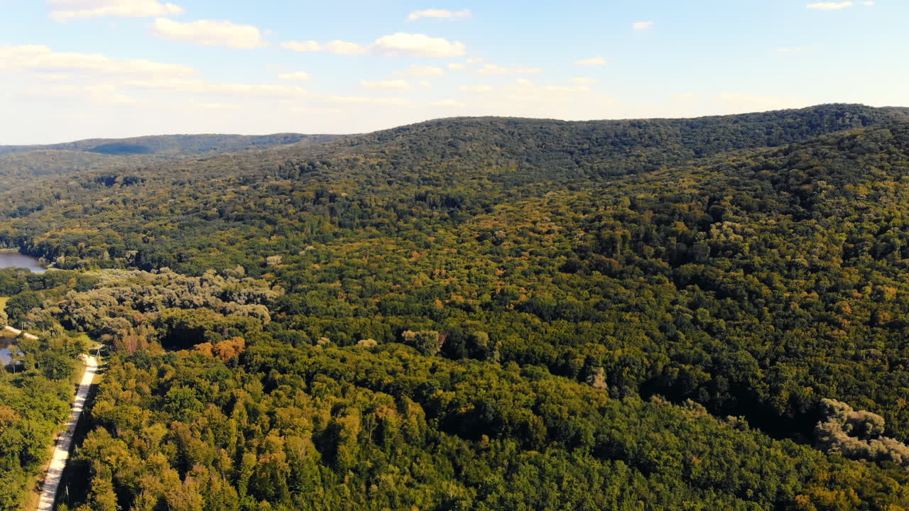 Aerial drone view of a village among greenery in Moldova. Lake and green hills. Panorama view. Sunny day