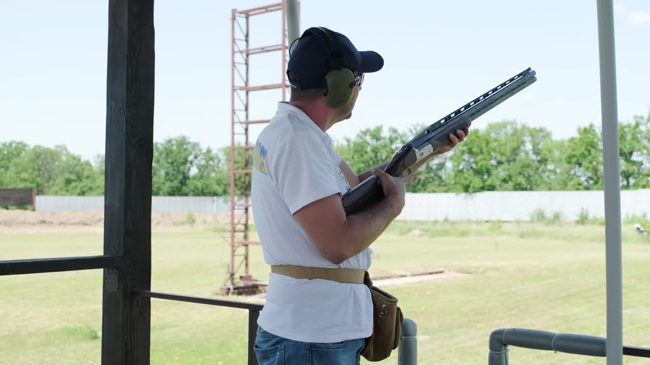 스포츠맨이 이중 배럴 건으로 총을 고, 슈팅 테스트를 위한 스포츠 경기장은 날아다니는 스케이트를 고 있습니다.