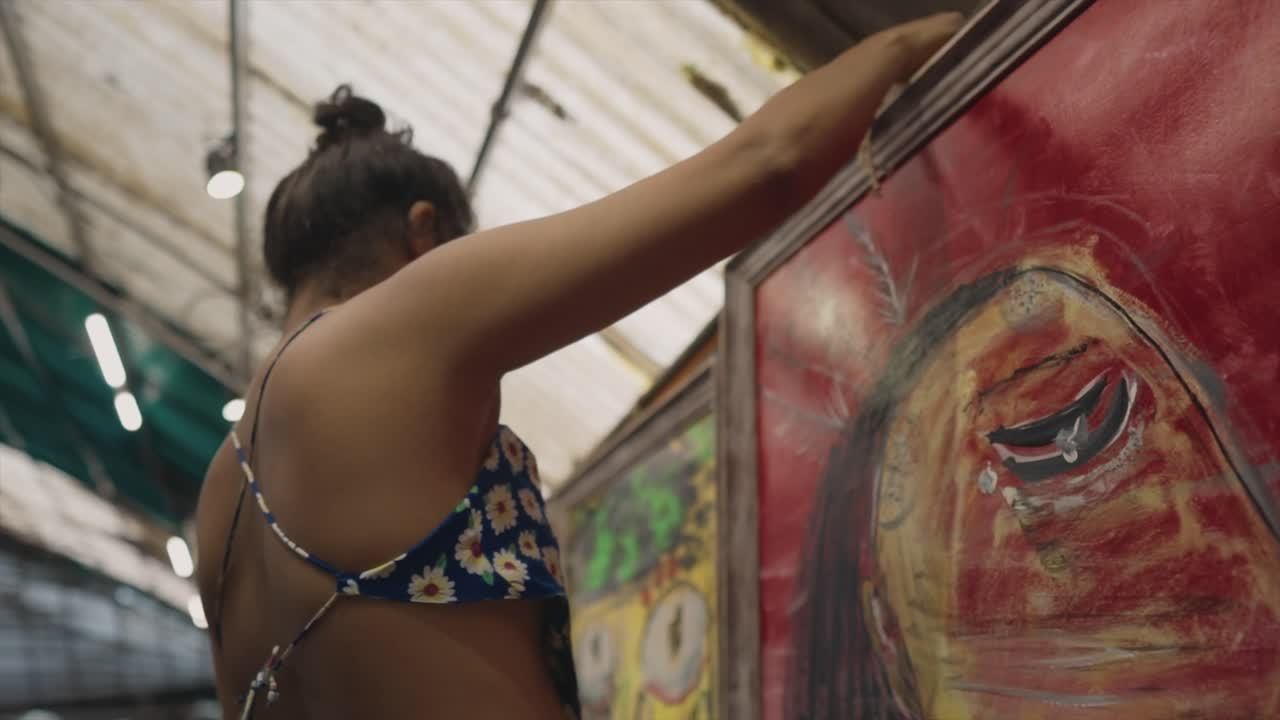 Linda garota pendurando uma pintura na parede - Obra de arte.