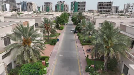 aerial drone view of street lined with uniform houses near a large city in bahria town, karachi, pakistan