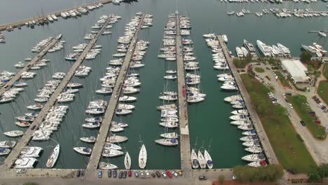 flight over the yacht marina filled with modern sailboats, aerial shot, camera moves to the left