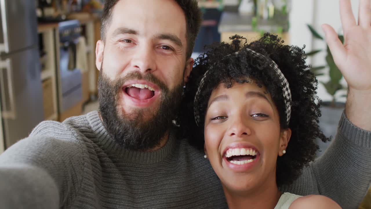 video de una pareja feliz y diversa hablando, saludando y soplando besos, haciendo una videollamada en casa