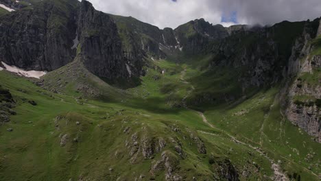 Un-Exuberante-Valle-Verde-Ubicado-Entre-Los-Picos-De-Las-Montañas-De-Bucegi,-Con-Un-Cielo-Azul-Claro-Y-Un-Terreno-Accidentado.