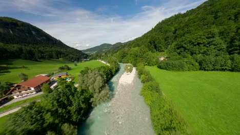 drone fpv volando sobre un río con agua turquesa en las montañas verdes de austria