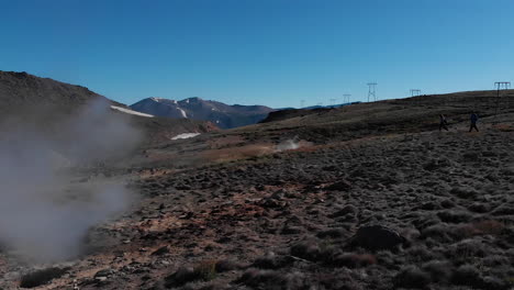 Aéreo---Gente-Caminando-Junto-A-Géiseres,-Caviahue,-Patagonia-Argentina,-Dando-Vueltas-En-Cámara-Lenta