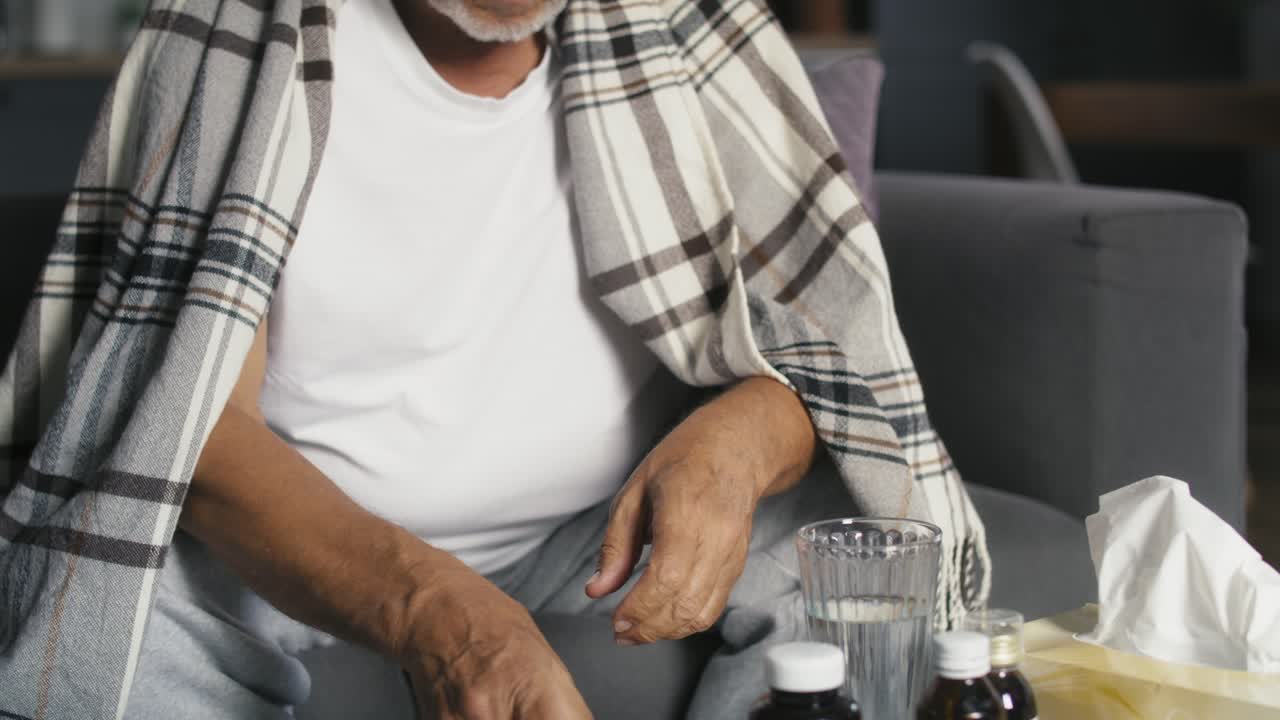 un hombre caucásico mayor eligiendo píldoras durante la gripe.
