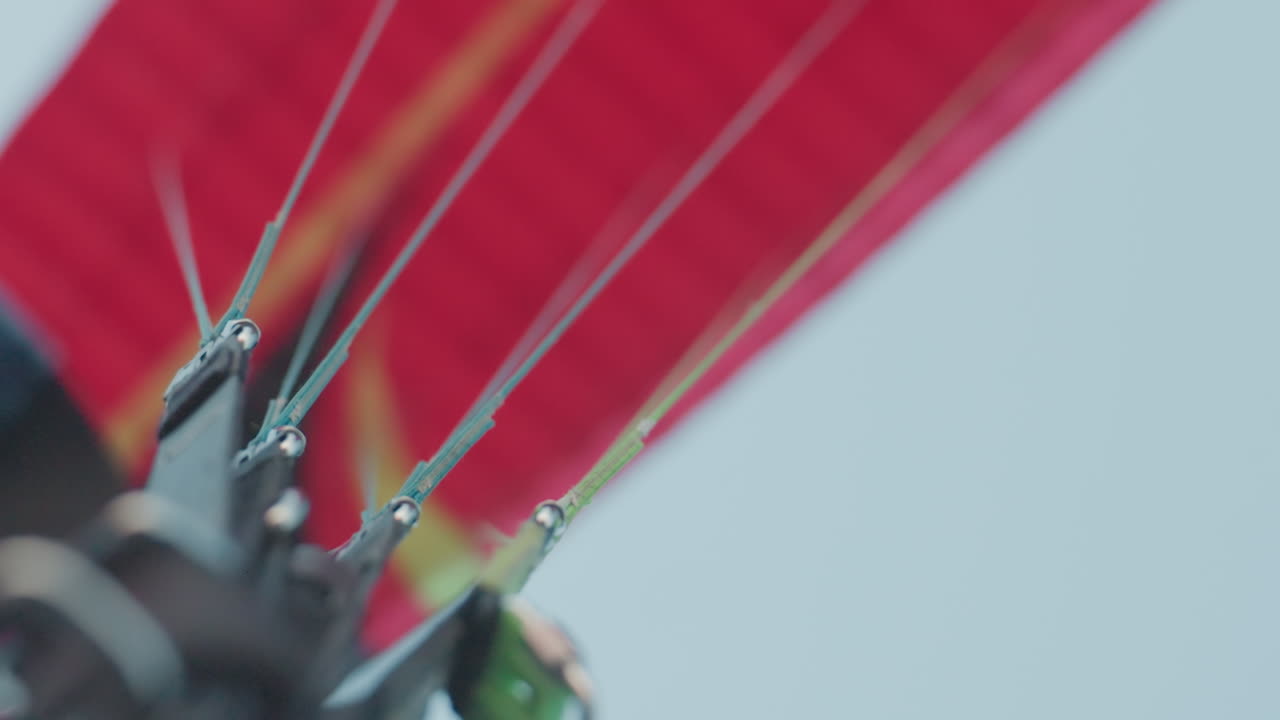 Closeup of vibrant paraglider canopy lines stretching into clear blue sky under soft dusk light showcasing detailed rigging and soaring adventure mood amid drifting clouds vibe