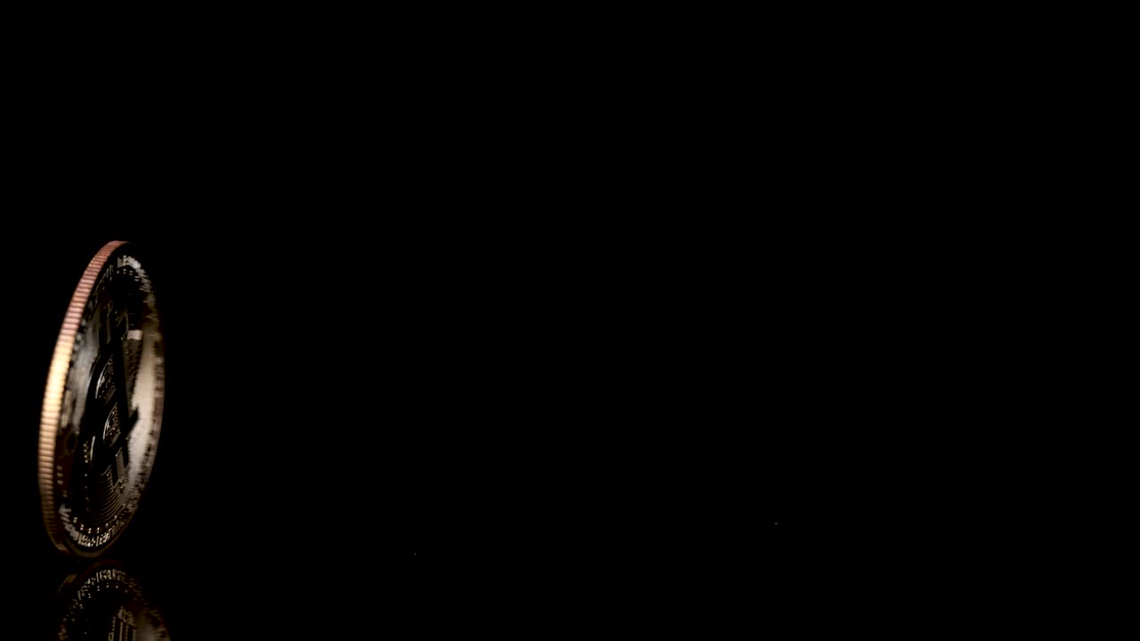 Gold cryptocurrency coin spins upright, reflecting light on glossy black background, slow-motion macro shot